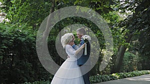 Happy newlyweds walk in the park holding hand, hug kiss.