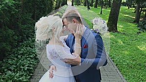 Happy newlyweds walk in the park holding hand, hug kiss.