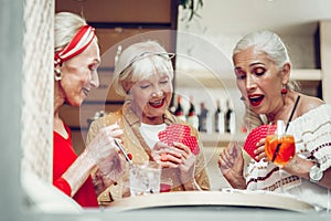 Happy nice elderly women playing cards together