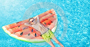 Happy nine years old caucasian child boy in red sunglasses having fun on air inflatable mattress in form of a watermelon.