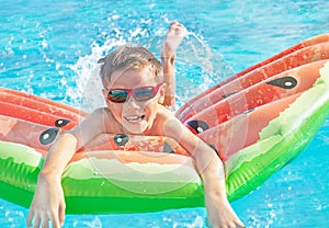 Happy nine years old child boy in red sunglasses playing with inflatable ring air mattress in the sea. Caucasian kid.