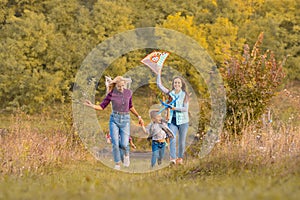 Happy non traditional family of two young mother and their kids launch a kite on nature at sunset