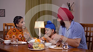 Happy nuclear Sikh family including a small child having dinner together at the table - family concept