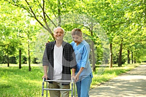 Happy nurse assisting elderly man with walking frame