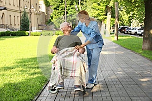 Happy nurse assisting elderly man in wheelchair