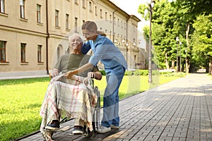 Happy nurse assisting elderly man in wheelchair