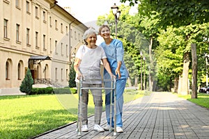 Happy nurse assisting elderly woman with walking frame