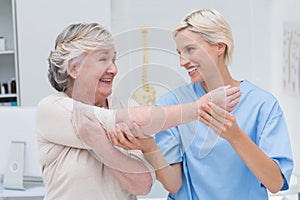 Happy nurse assisting patient in raising arm