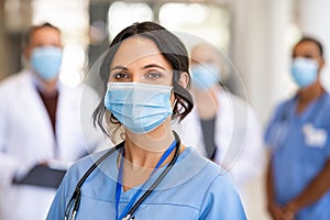 Happy nurse with face mask smiling at hospital