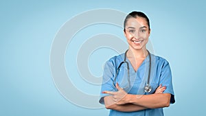 Happy nurse pointing left at free space, wearing blue scrubs