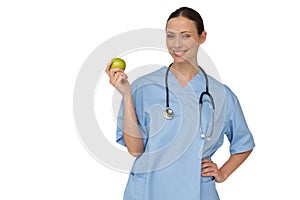 Happy nurse in scrubs holding green apple