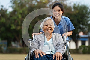 happy nurse take care and pushing senior woman in wheelchair at park, friendly caregiver