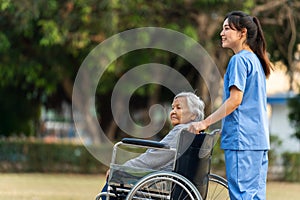 happy nurse take care and pushing senior woman in wheelchair at park, friendly caregiver