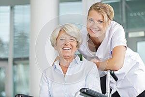 Happy nurse taking care senior woman in wheelchair