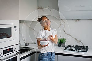 Happy nutritionist woman holds a fresh cherry berry in a plate in her hand. The concept of healthy eating and diet