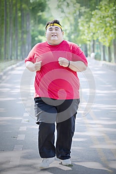 Happy obese man doing run exercises in the park