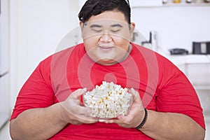 Happy obese man holding a bowl of popcorn