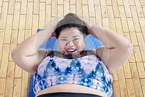 Happy obese woman doing crunches exercises