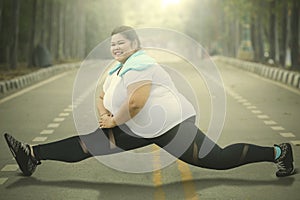Happy obese woman doing split exercise