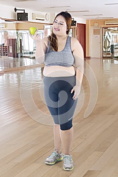 Happy obese woman holding a green apple