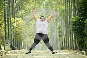 Happy obese woman jumps on the road