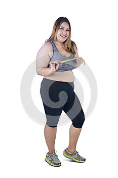Happy obese woman measures her chest on studio