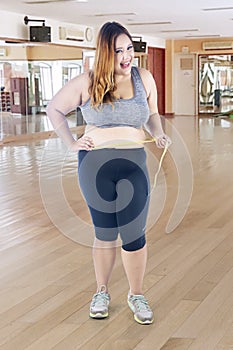 Happy obese woman measuring her tummy