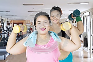 Happy obese women exercising with dumbbells