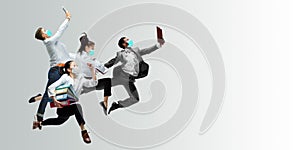 Happy office workers in face masks jumping and dancing in casual clothes or suit isolated on studio background. Creative