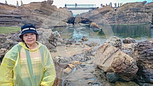 Happy Old asian women wear a rain roat and travel in taipei Yehliu geopark in rainy day