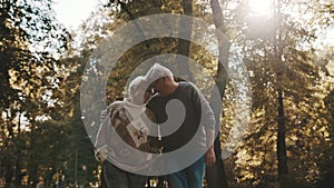 Happy old couple hugging in park. Senior man flirting with elderly woman. Romance at old age on autumn day
