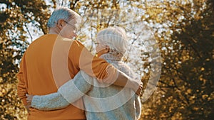 Happy old couple hugging in park. Senior man flirting with elderly woman. Romance at old age on autumn day