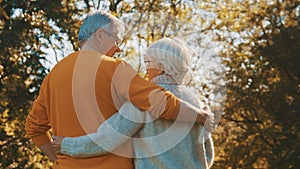 Happy old couple hugging in park. Senior man flirting with elderly woman. Romance at old age on autumn day