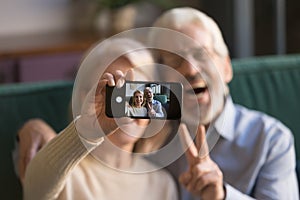 Happy old couple taking selfie on cellphone, focus on display