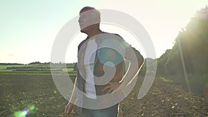 Happy old farmer in shirt standing and looking at his field with pleasant expression, beautiful view of nature during