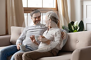 Happy old father relax on sofa with adult son