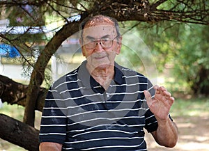 Happy old grandfather enjoying life waving hi, with big smile, big glasses and confident abuelo photo