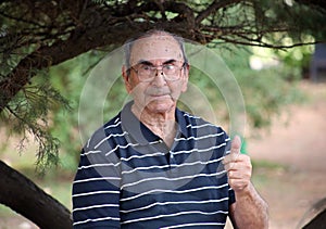 Happy old grandfather enjoying life waving hi, with big smile, big glasses and confident abuelo photo