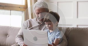 Happy old grandfather and grandson using laptop video calling