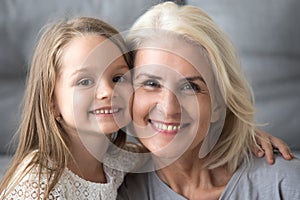 Happy old grandmother hugging smiling grandchild looking at came