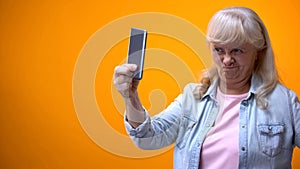 Happy old lady taking selfie on smartphone, showing grimace, modern technologies