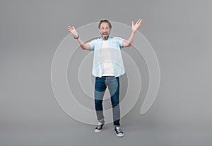 Happy old man in casual gesticulate with open arms grey background, welcoming