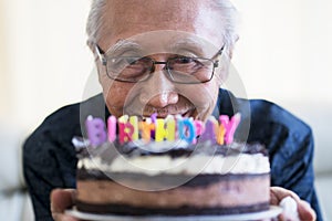 Happy old man holding chocolate birthday cake