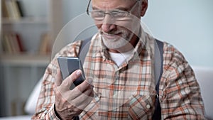 Happy old man holding phone, learning modern technologies, easy app for elderly