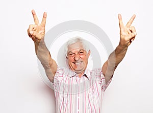 Happy old man showing victory sign, positive or peace gesture.