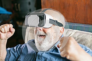 happy old man using virtual reality goggles at home