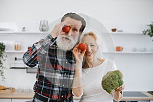 Happy old man and wife spend morning time in kitchen.