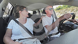 happy old man and woman having fun together while traveling on vacation dancing and singing while driving a car