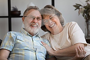 Happy old mature bonding married couple laughing at funny joke.