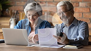 Happy old mature married couple calculating domestic utility bills.